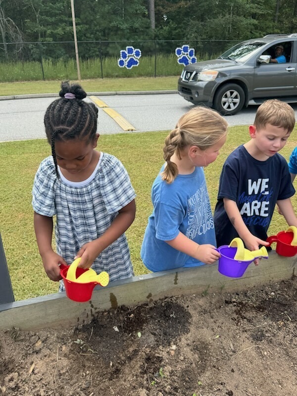 1st grade students planting and watering garden