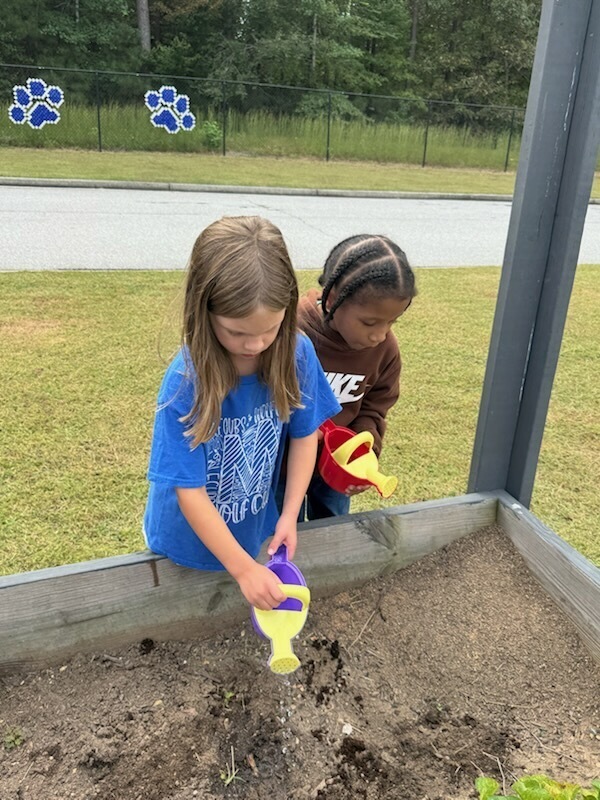 1st grade students planting and watering garden
