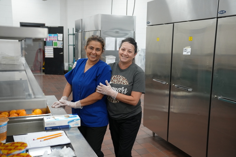 School Nutrition workers smile while preparing food.