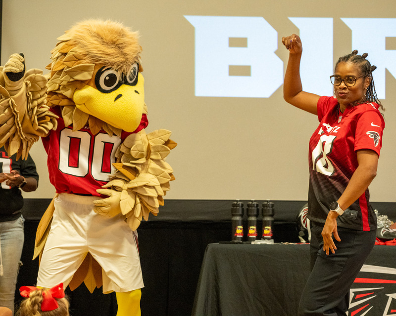 Arbor Station Principal Anitra Paige dances with Freddie Falcon during the mascot's visit to her school.