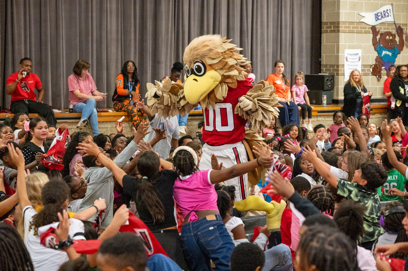 Freddie Falcon gives high-fives to students at Arbor Station Elementary.
