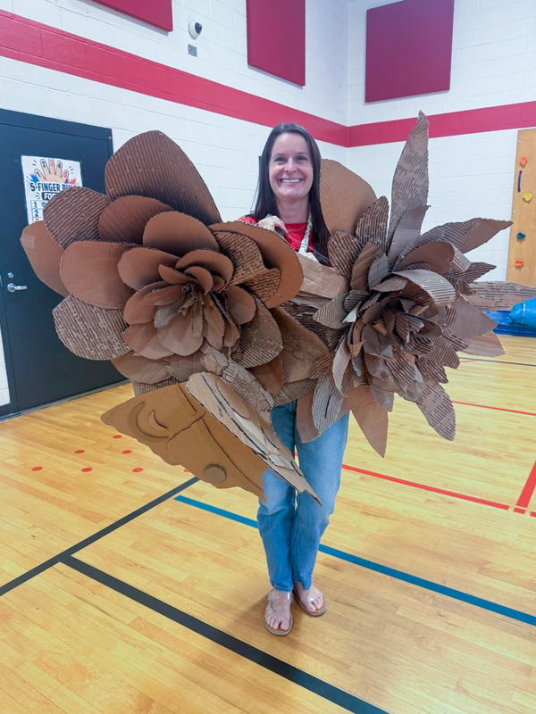 Winston Elementary art teacher Julia Sweeney poses with the floral sculpture she and her students created.