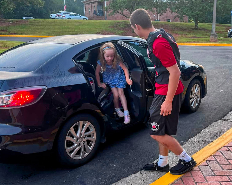 An AHS football player opens the door for a South Douglas Elementary student.