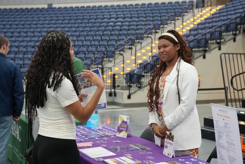 A student talks with a woman from a college during the Probe College Fair.