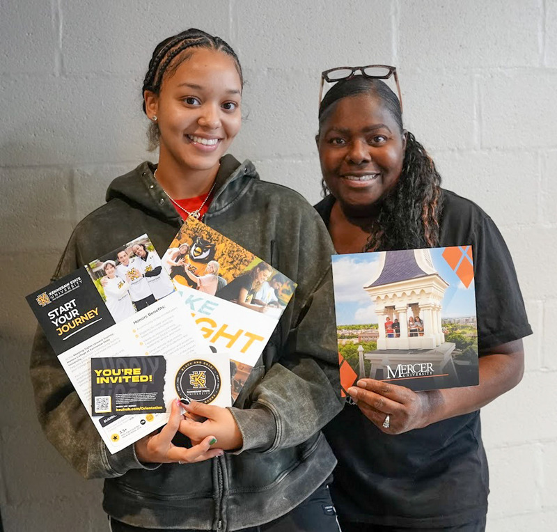 Two students hold up brochures from colleges during the Probe College Fair.