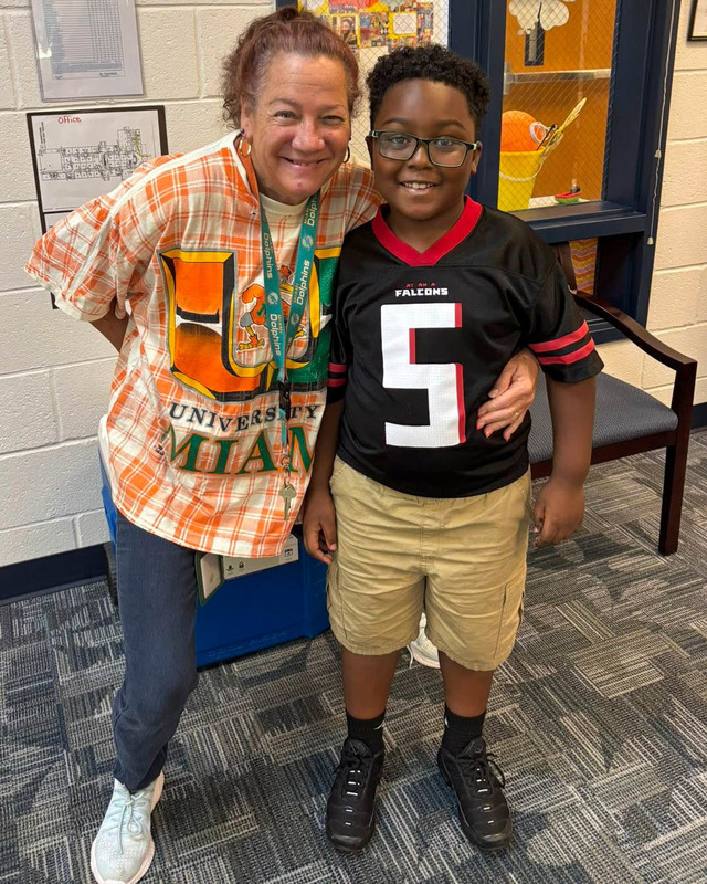 A teacher and student dressed in college/pro football gear.