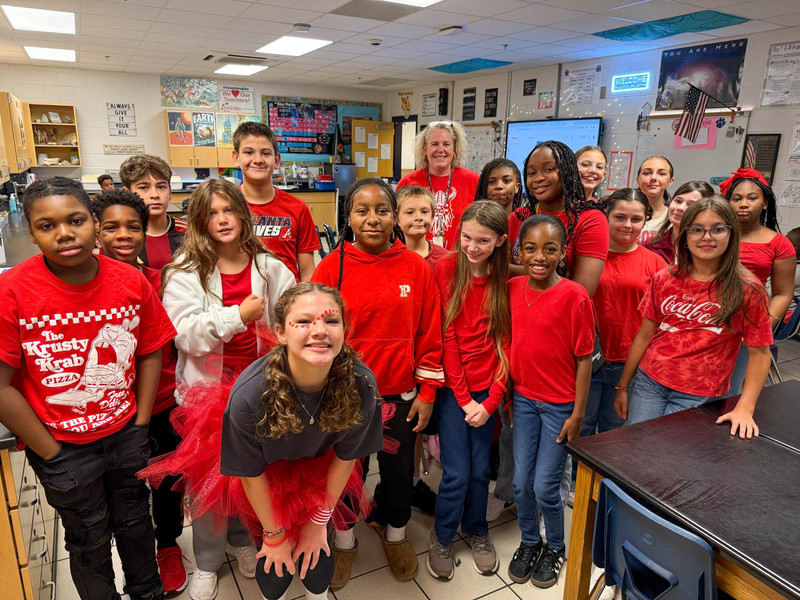 FMS teacher Lydia Palmer and students dressed in red for the House Meeting.