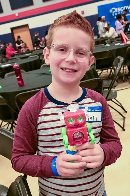 A student holds up a robot at Google Family STEM Day
