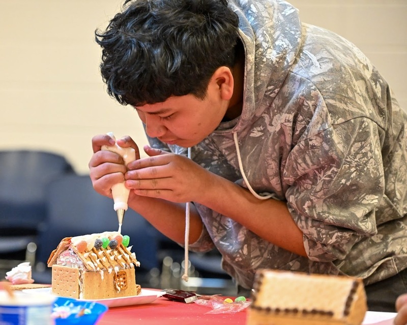 A Newcomer Student puts icing on his gingerbread house.