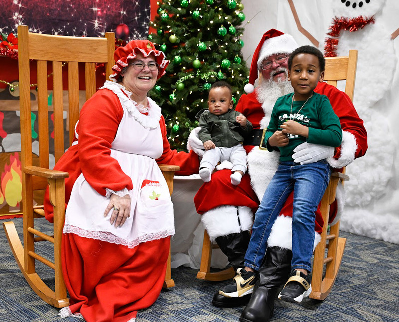 Two children have their photo made with Santa and Mrs. Claus at the LEAP Christmas Party.