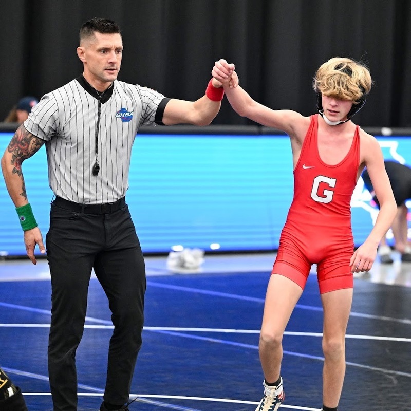 A ref raises the arm of a Gainesville wrestler after a win.