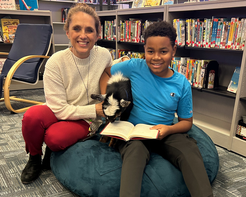 Media specialist Elizabeth Shadix and a student with a book and one of the new reading goats.