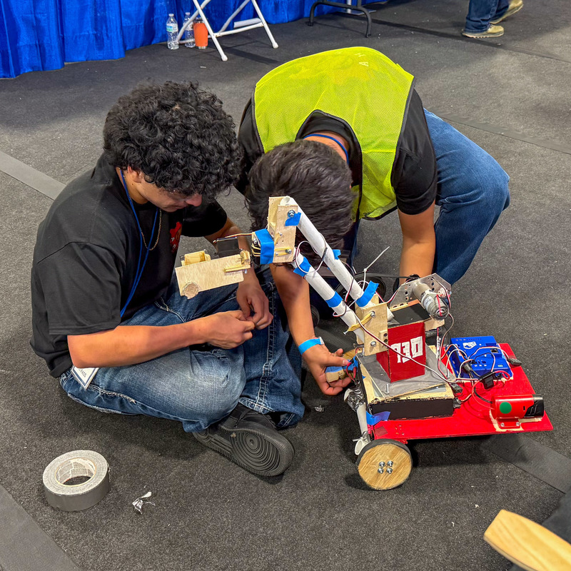Two Alexander students work on a robot.