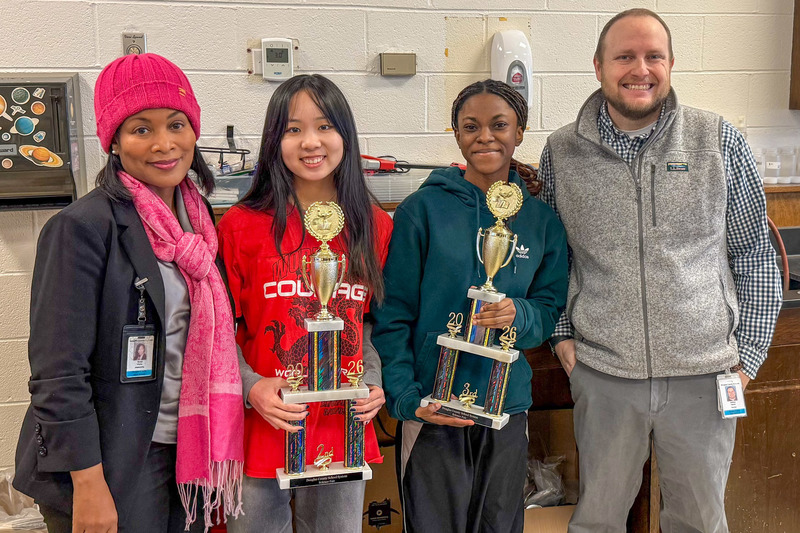 Douglas County High School second place winner Sophia Yang and third place winner Alysha Gayle hold their trophies alongside Principal Kenja Parks and science teacher Andrew Adams after the district science fair.