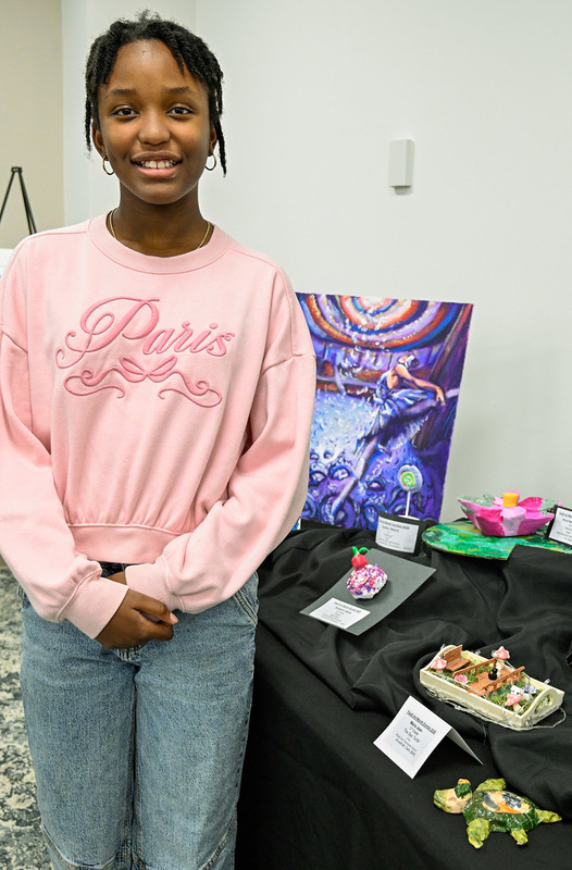 A student stands next to her sculpture at the Youth Art Show.