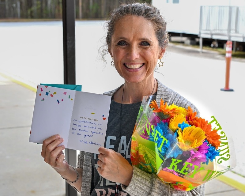 Bright Star Media Specialist holds up her celebratory card and flowers for winning Media Specialist of the Year.