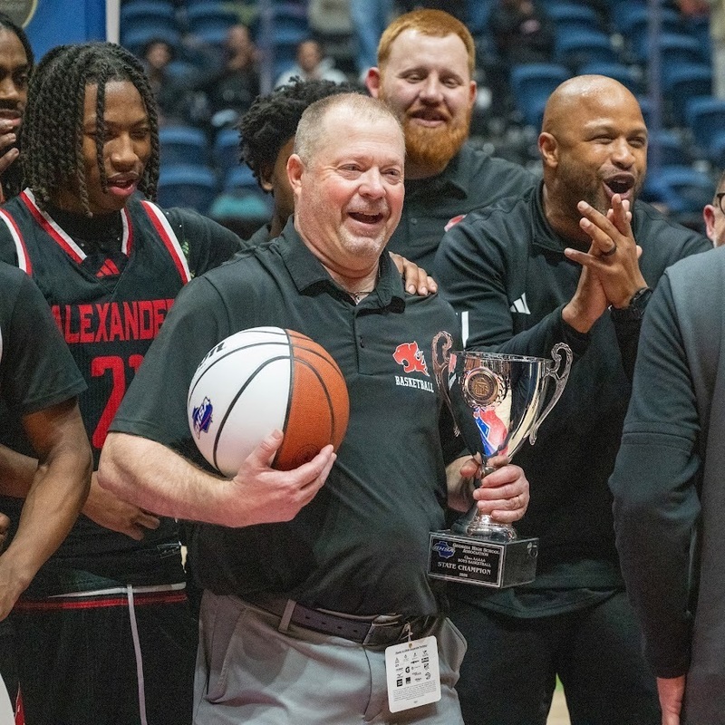 Alexander boys basketball coach holds the championship trophy after the Cougars 81-67 win over Woodward in the title game.