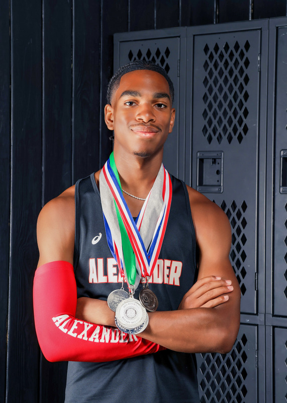 Cantrell Etheridge is pictured wearing track medals while standing in front of lockers.