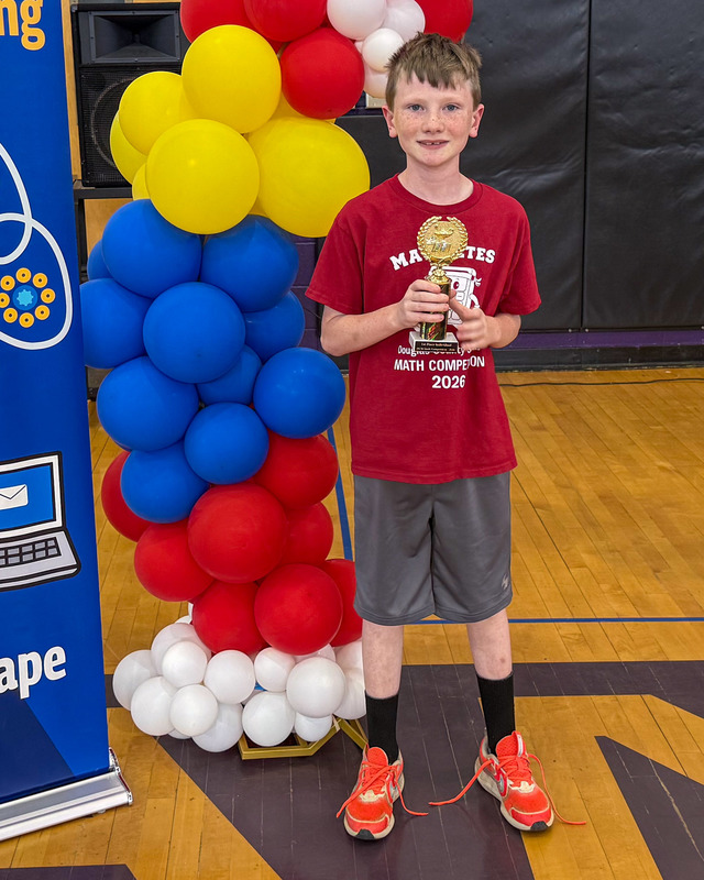 An elementary student holds up his first place trophy in the math competition.