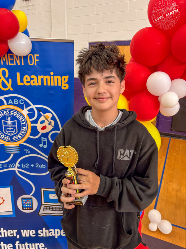 A middle school student holds up their trophy for winning the math competition.
