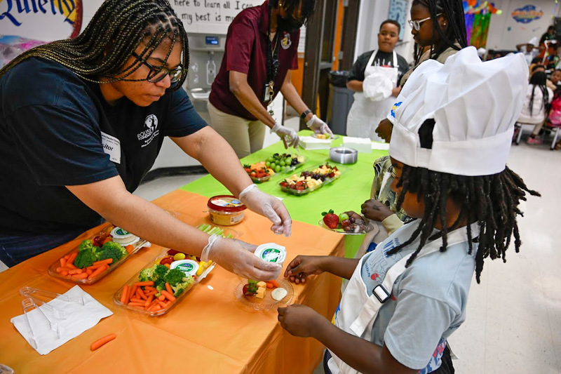A member of the Rouse Foundation hands a Sweetwater student some heart healthy food items.
