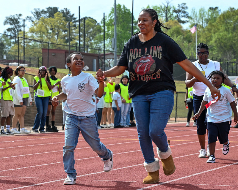A DCSS student looks up at his mom with a smile as they two run a race during the Special Olympics.
