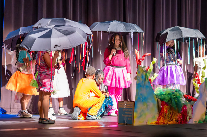 Sweetwater students hold umbrellas with colorful streamers to look like jellyfish in Finding Nemo: Kids.