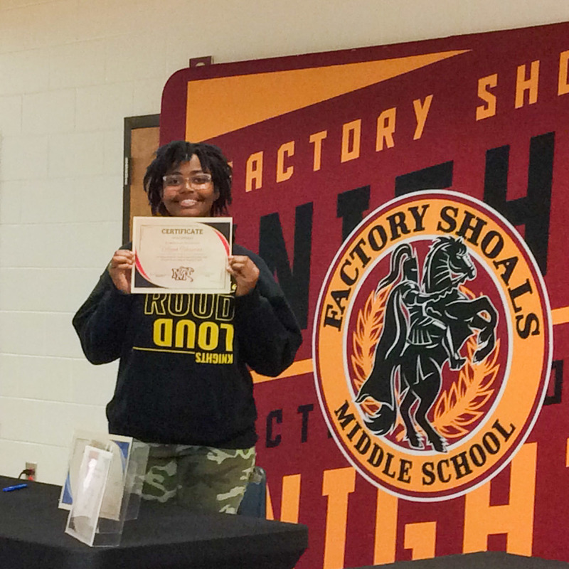 A student at Factory Shoals Middle holds up a certificate declaring her intent for high school magnet program.