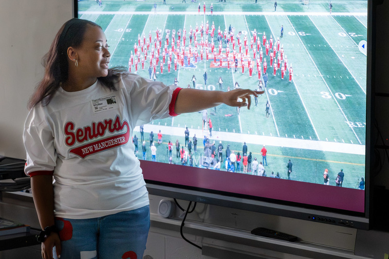New Manchester High senior Chandler Howard shows CHES students a video of the New Manchester High band performing while pointing to herself in the video.