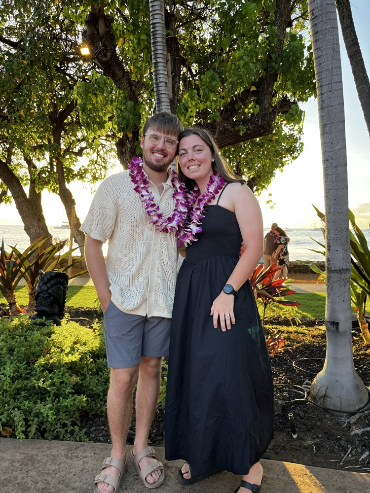 couple standing in front on trees and ocean
