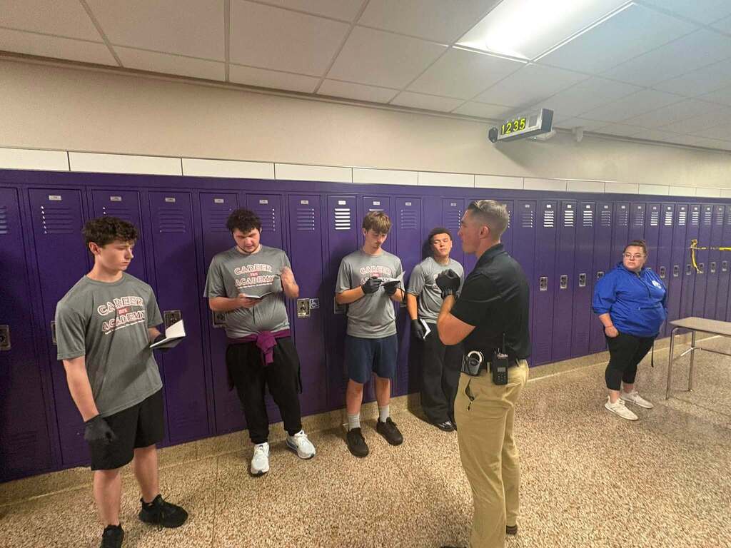 students gather around listening to an officer with notepads out