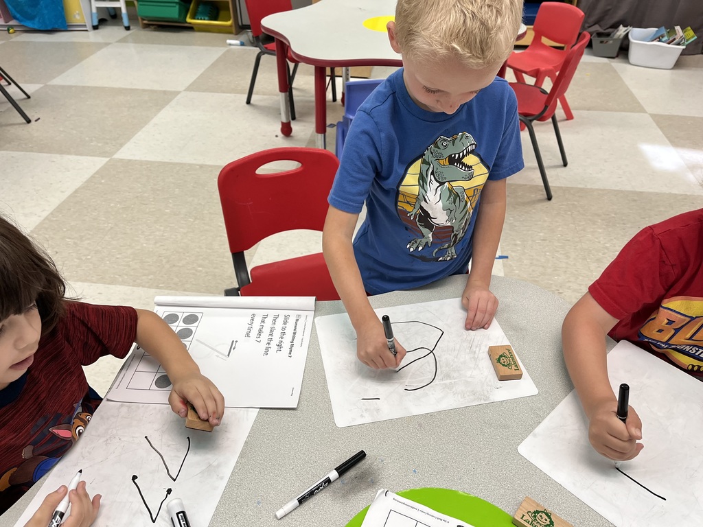 young students writing on paper with crayons