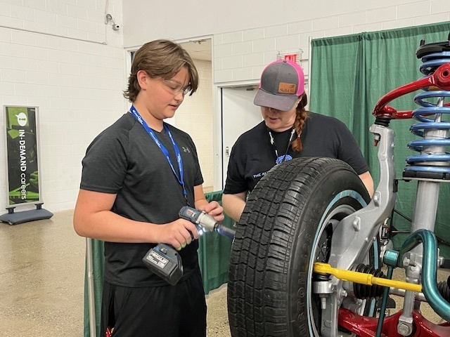 student practicing on a tire with adult supervision
