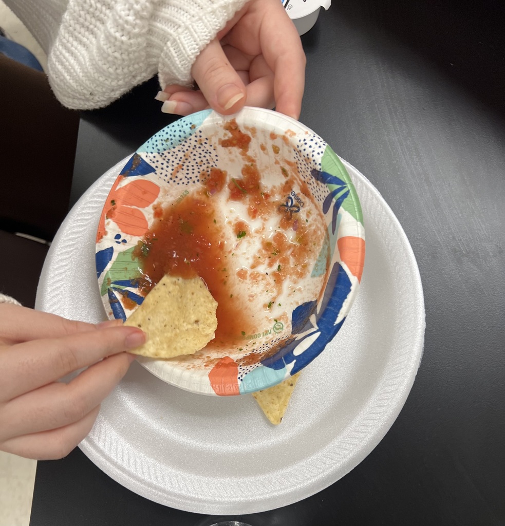 a hand dipping a chip in fresh salsa