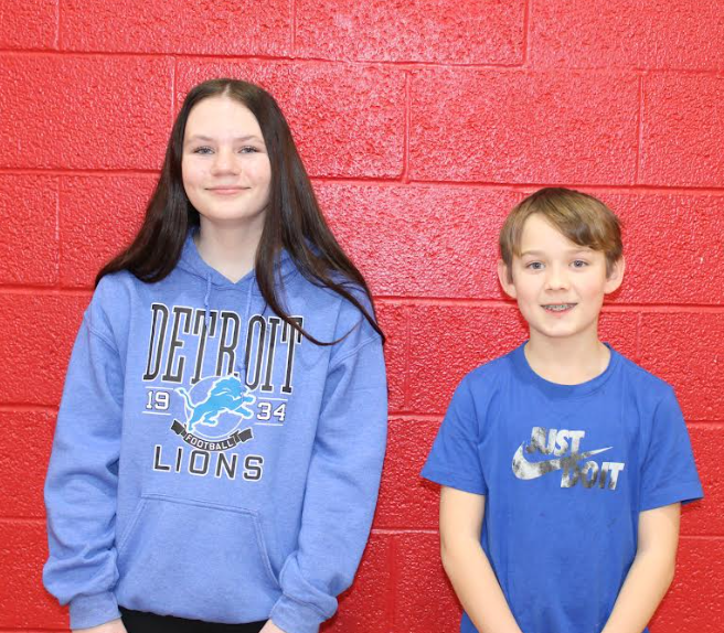 two students in front of a red background