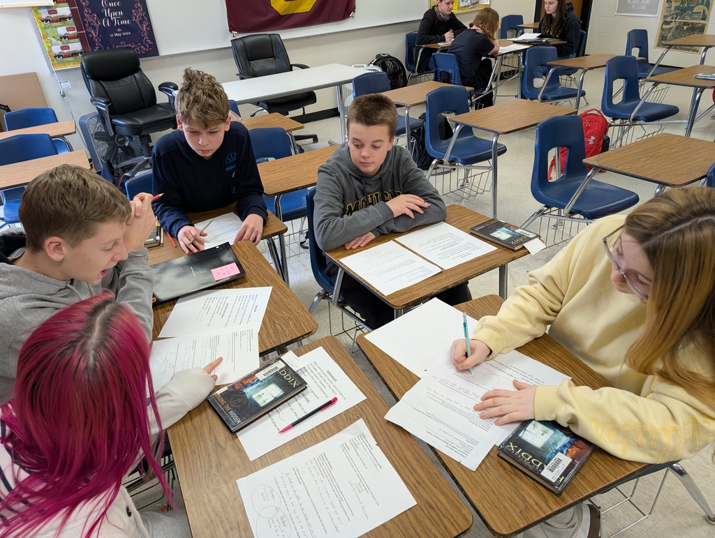 students sitting at desks having a small group discussion