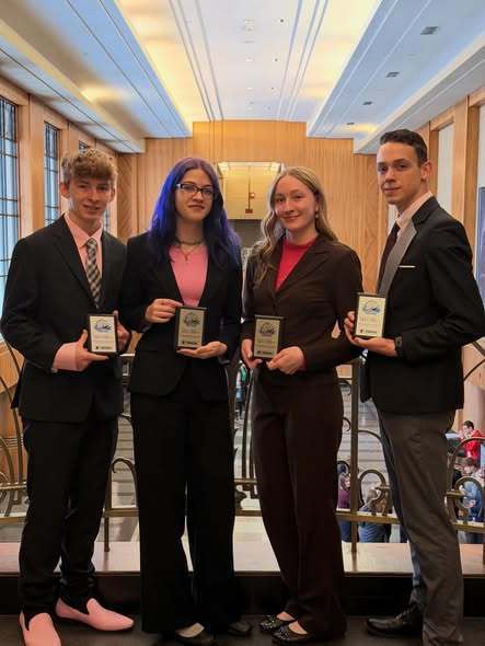 photo of four high school students, professionally dressed and holding plaques