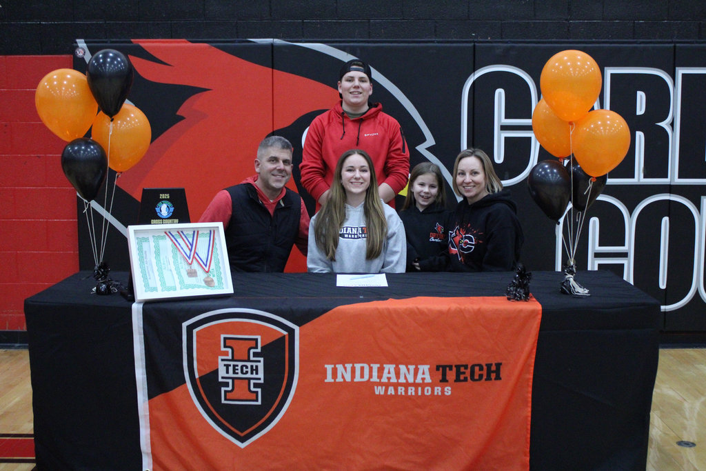 family (two parents, three children) standing/sitting behind a table