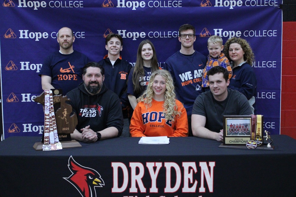 photo of a high school athlete sitting behind a table with family and coaches