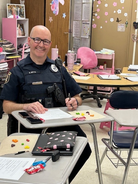 school resource officer sitting at a student desk