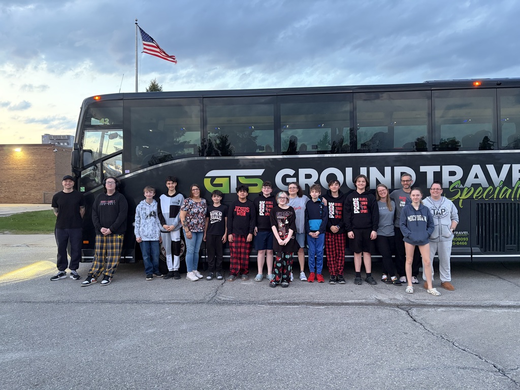 group of students and parents standing in front of a bus