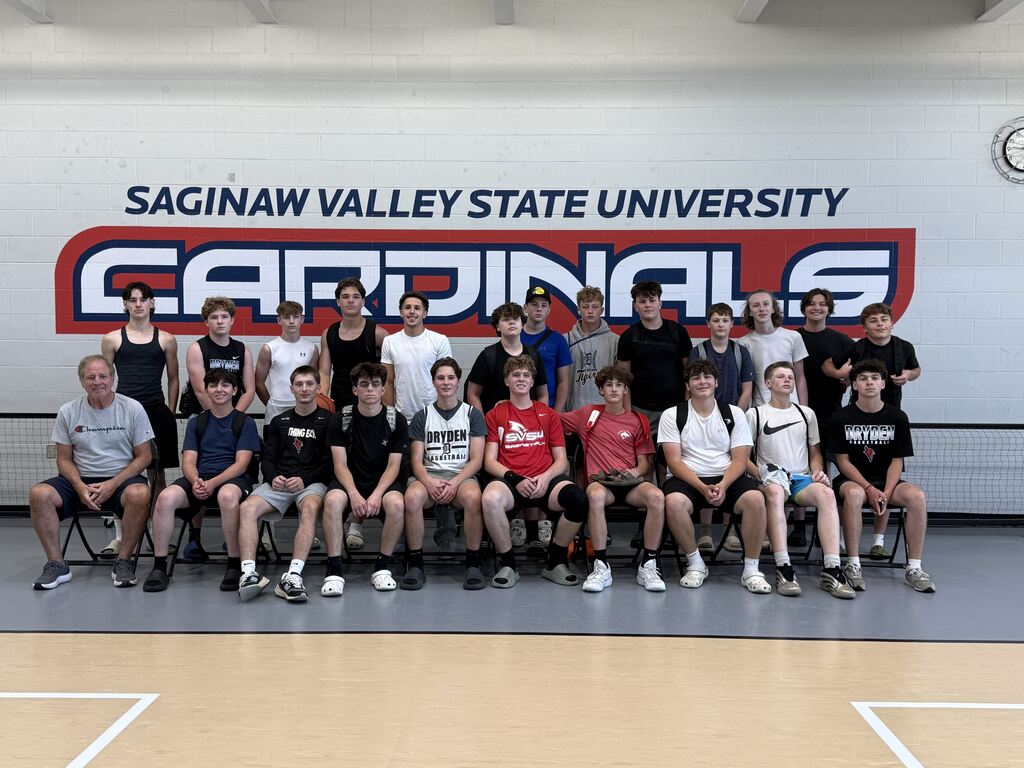 two rows of high school male athletes and a coach sitting in chairs