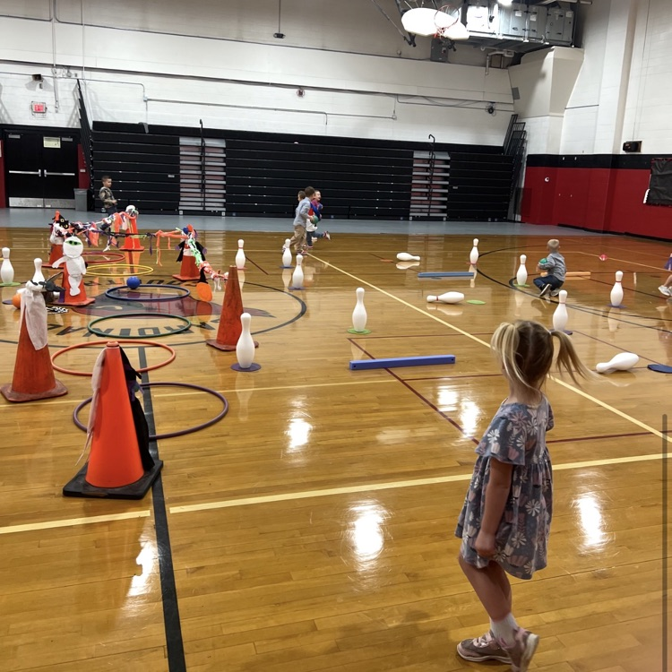 Students during PE class are practicing teamwork, good sportsmanship, rolling a ball towards a target, addition and cardio during the activity “trick or treat” bowling.