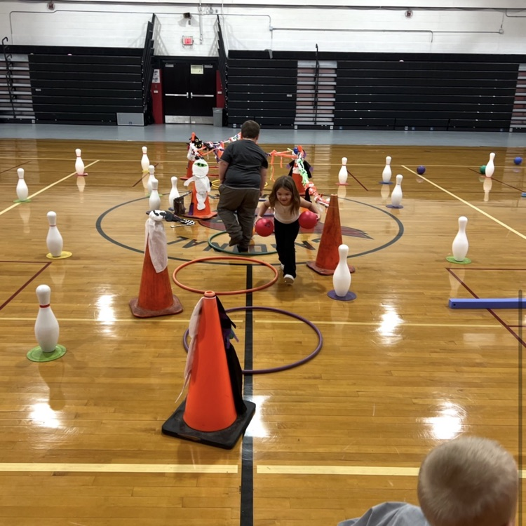 Students during PE class are practicing teamwork, good sportsmanship, rolling a ball towards a target, addition and cardio during the activity “trick or treat” bowling.