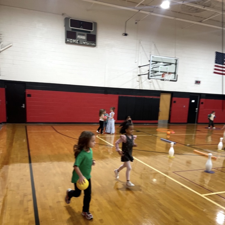 Students during PE class are practicing teamwork, good sportsmanship, rolling a ball towards a target, addition and cardio during the activity “trick or treat” bowling.