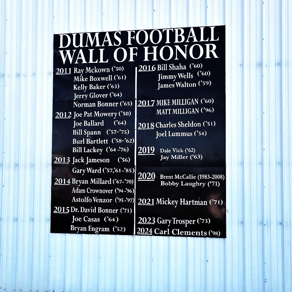 Dumas High School Wall of Honor sign is shown hanging on the side of the Demon Dome. The sign lists the names and the year for each wall of honor recipient.
