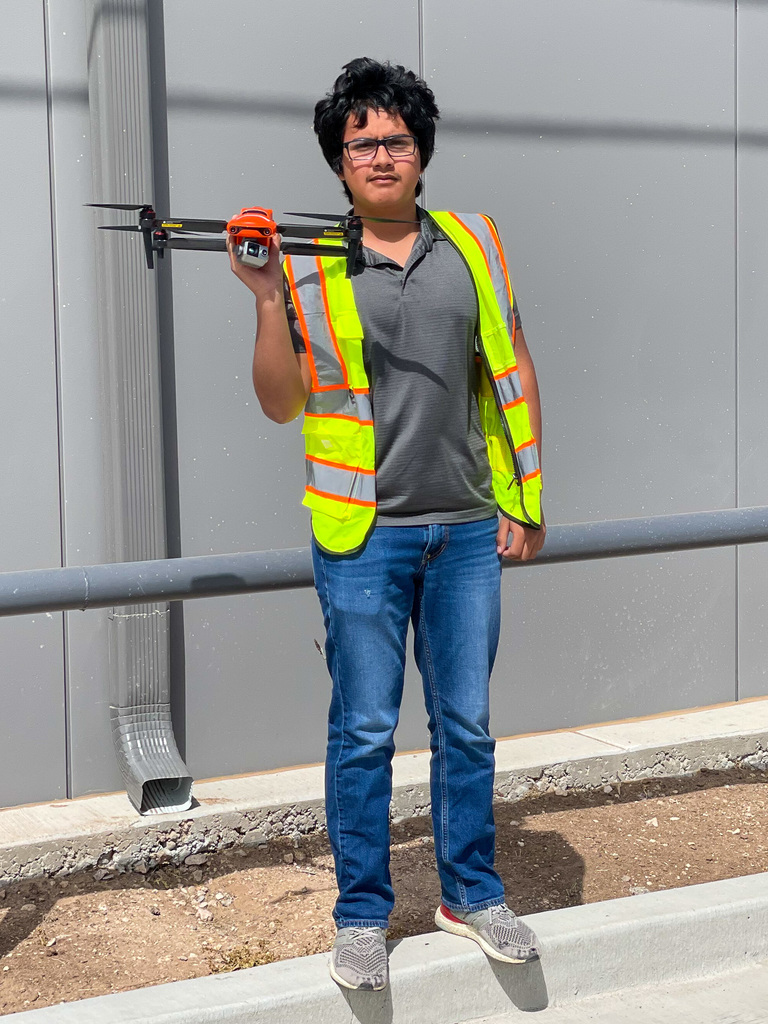 Student Eliseo Medina holding a drone in front of the new CTE building