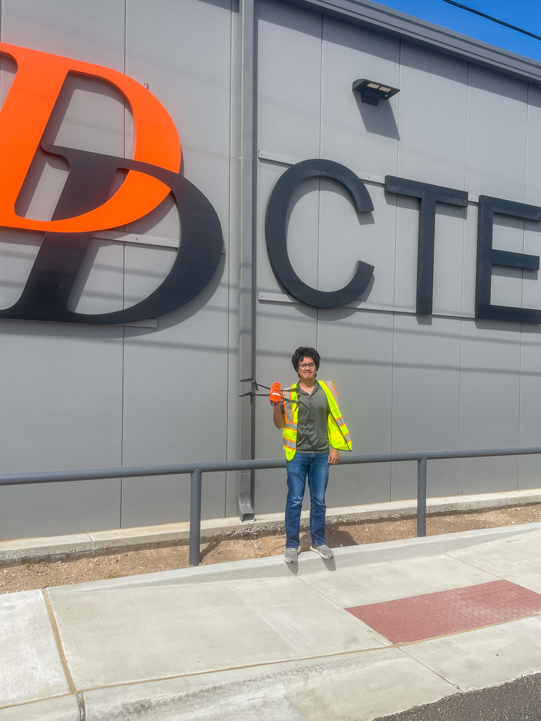 Student Eliseo Medina holding a drone in front of the new CTE building