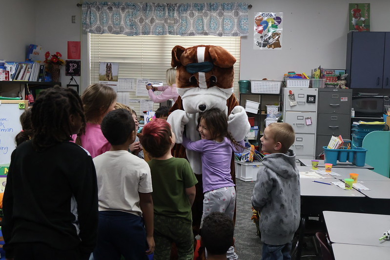 students hugging champ the humane society mascot