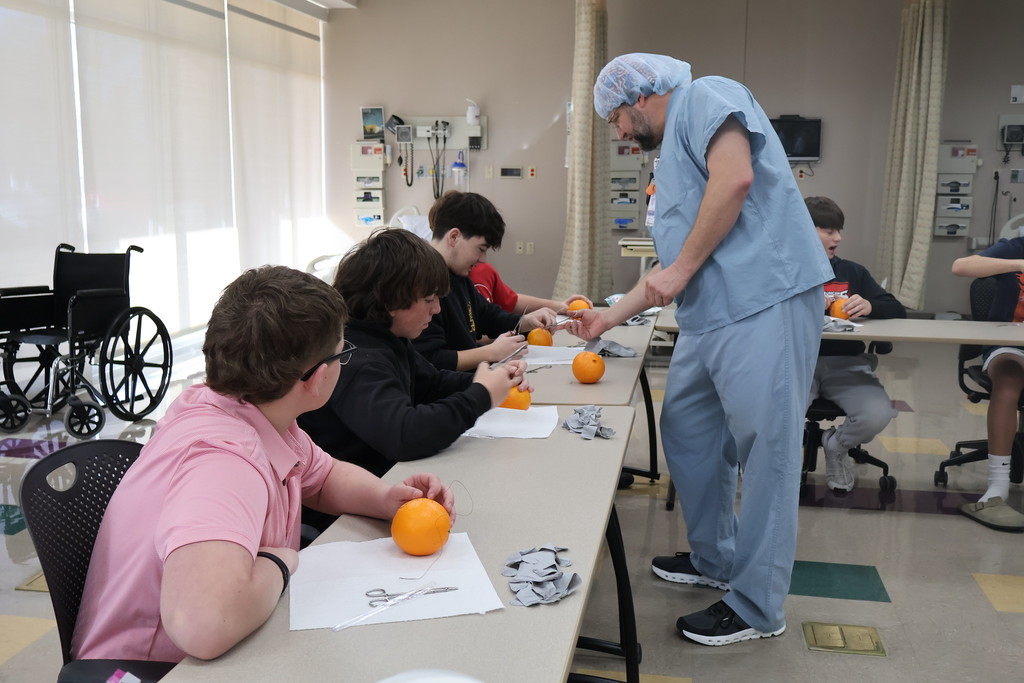 student stitching an orange